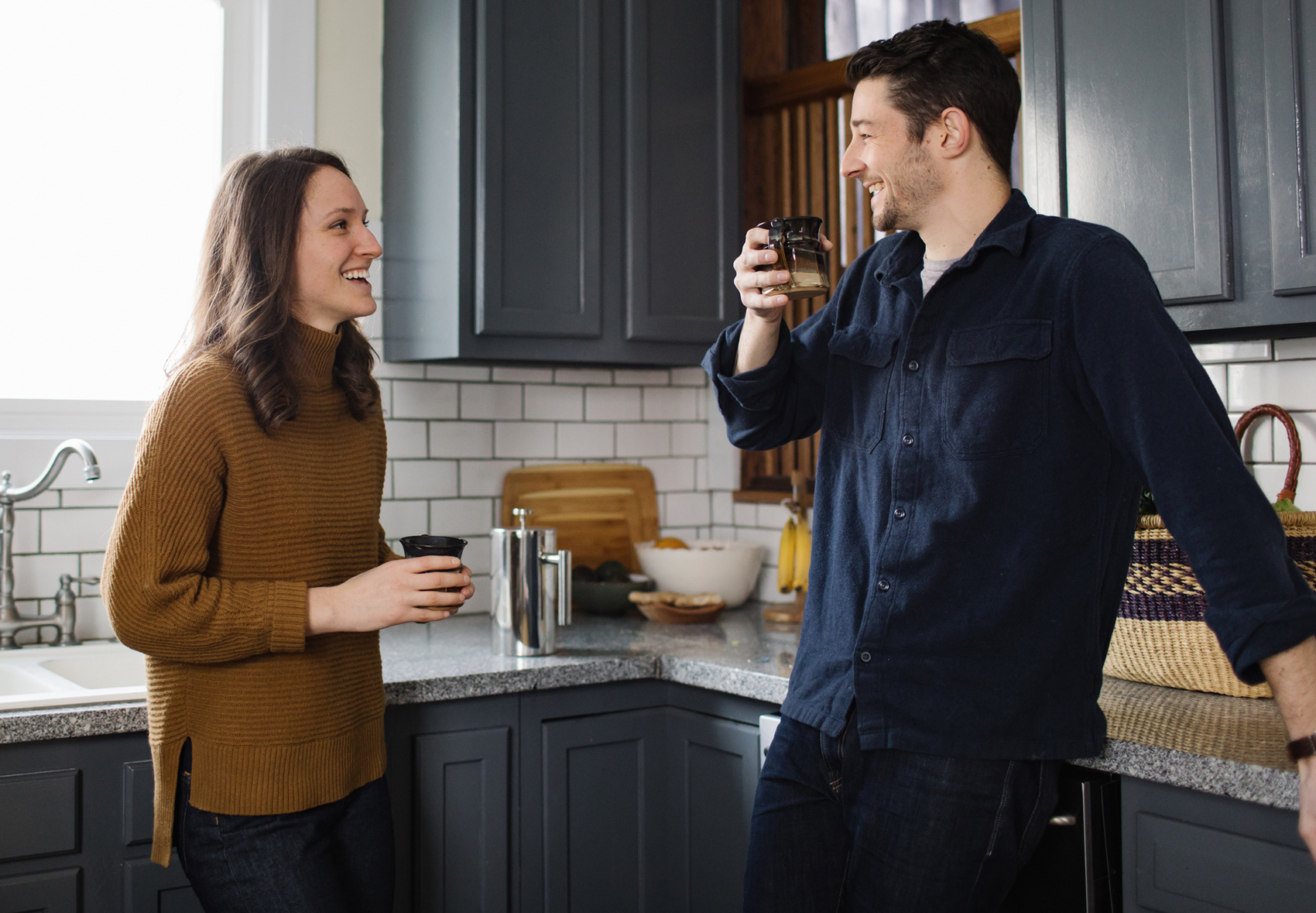 a couple in a kitchen drinking coffee and smiling
