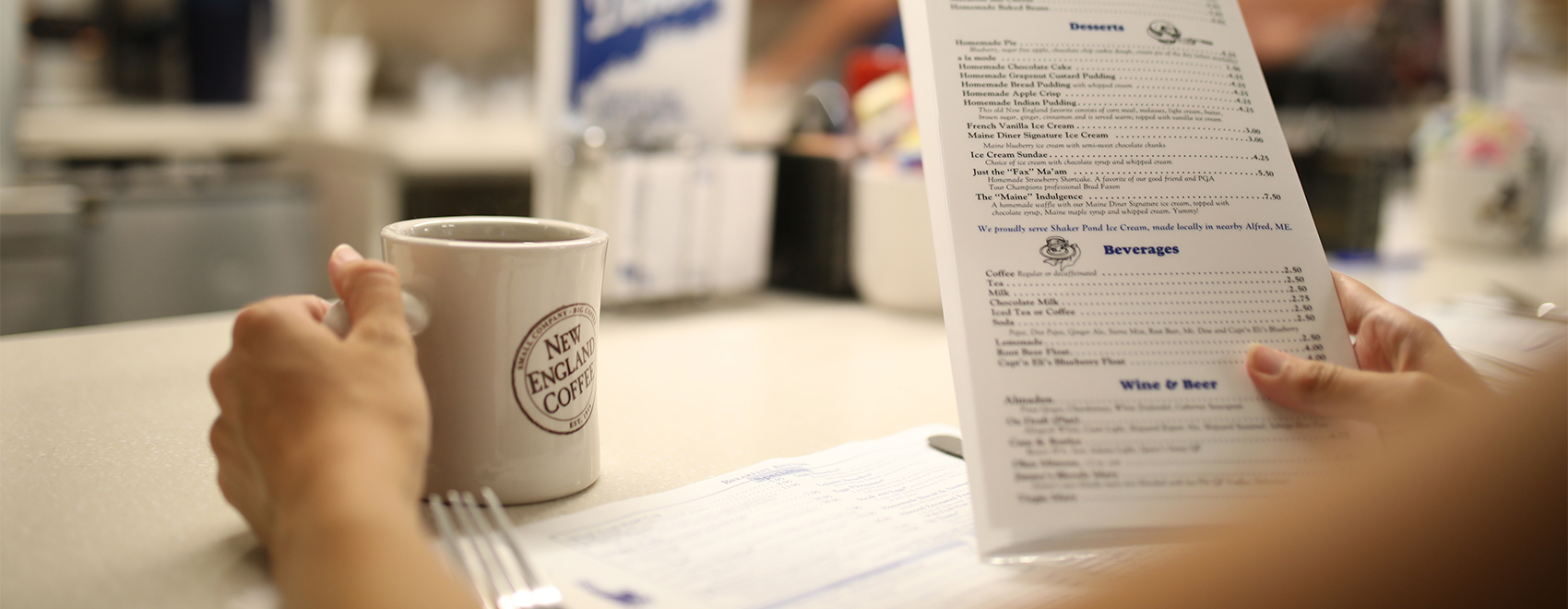 Coffee cup and customer reading menu